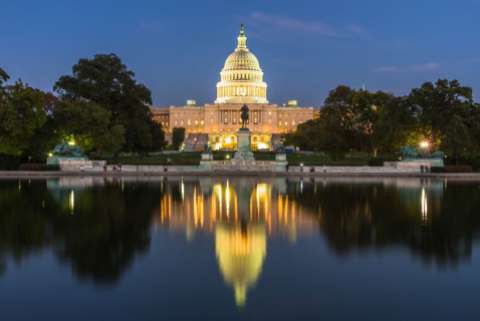 The US Capitol building shown at dusk, with the building's reflection apparent in a reflecting pool