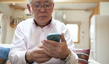 an elderly man looks at his smartphone suspiciously