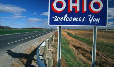 An "OHIO Welcomes You" sign by the side of a highway