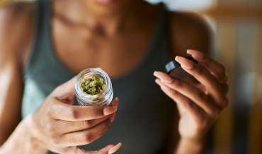 A woman examines a jar of legal marijuana buds