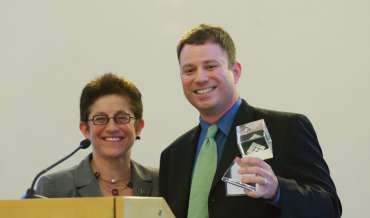 Gigi Sohn smiles with Mike Masnick, who is holding some sort of award