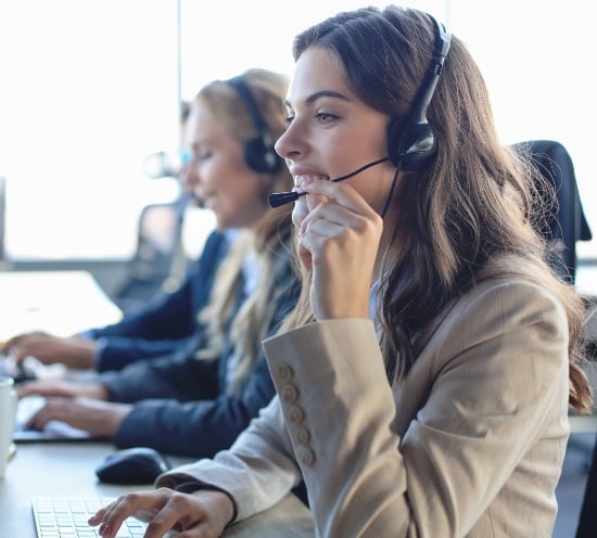 female-customer-support-operator-with-headset-smiling-with-collegues-background (1)
