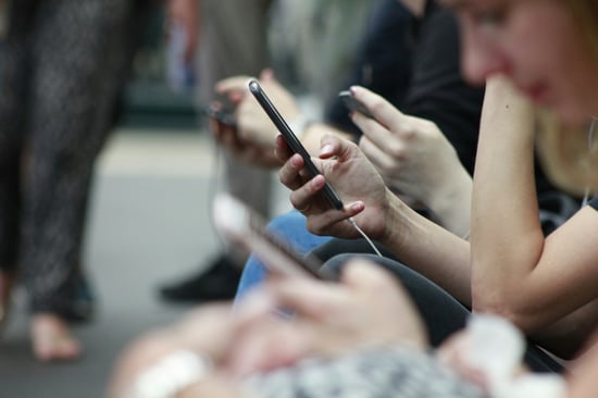 row of people with cell phones in hand