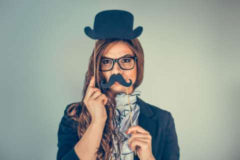 A woman with an obviously fake mustache and fake bowler hat