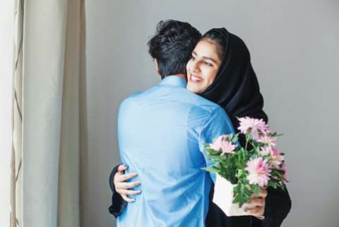 Happy muslim woman getting flowers as a gift from her relative on muslim celebration