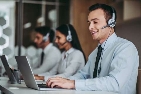 call center employees wearing headsets and typing on laptops