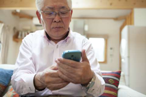 an elderly man looks at his smartphone suspiciously