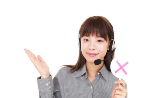 A woman with a headset telephone raises her right palm and holds a sign with a red X in her left hand