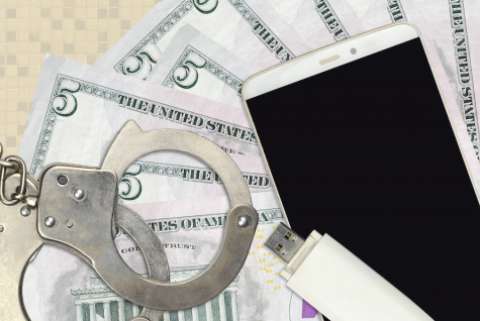 still life with handcuffs, smartphone, flash drive, and five dollar bills (american)