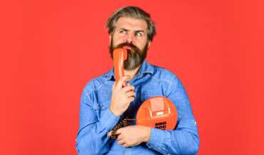 A bearded man cradles an orange phone with a plaintive look on his face